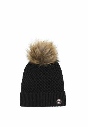 Cappello invernale nero lavorato a maglia con un grande pompon in ecopelliccia marrone sulla sommità e un piccolo logo circolare sul risvolto piegato.