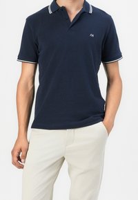 Marinepoloshirt met knoopsluiting met twee knopen, witte accenten op de kraag en mouwen, en geborduurd logo. Zachte stof met een normale pasvorm.