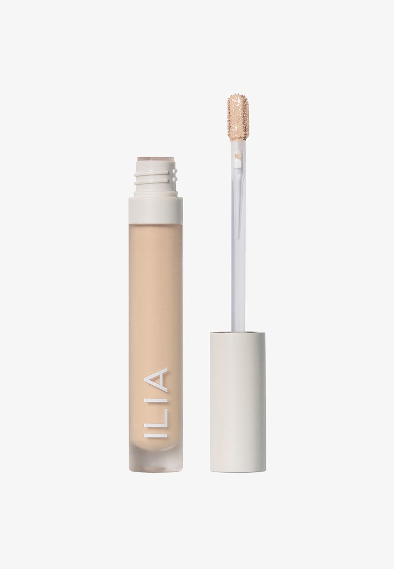 Flytande concealer i en genomskinlig tub med en beige nyans. Har en mjuk applikator med en texturerad spets och ett vitt lock.