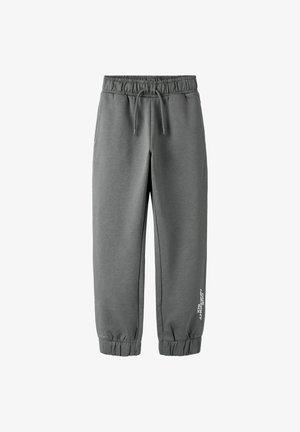 Szare spodnie dresowe z miękkiego materiału. Elastyczny pas z sznurkiem, zwężane ściągacze i biały napis po boku.