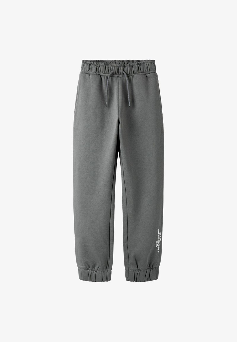 Grå joggebukser laget av mykt stoff. Elastisk linning med snor, tilspissede mansjetter og hvit tekstdetalj på siden.