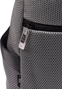 Mochila gris con un exterior de malla, que cuenta con un bolsillo con cremallera, una superficie texturizada y una pequeña etiqueta transparente con el logo "K3".
