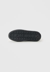 Semelle de sneaker en caoutchouc noir avec une surface texturée, comportant un logo proéminent et des motifs d'étoiles pour une meilleure adhérence et un détail de design.