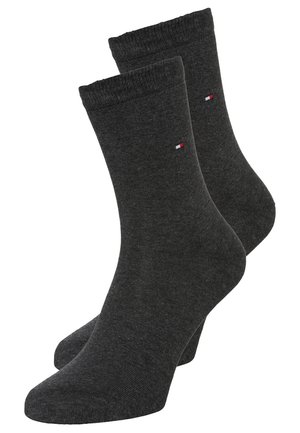 Kolsvarthuvud bomullssockor med ribbade muddar och en liten broderad logotyp i rött, vitt och blått nära toppen. Slät textur.