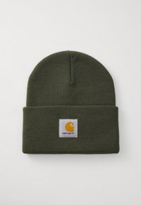 Green knitted beanie hat with a cuff. Features a square white patch displaying a yellow logo and brand name "Carhartt" in black lettering.