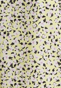 Tecido amarelo com um padrão floral apresentando flores brancas e cor-de-rosa contornadas a preto, criando um design vibrante e texturado.