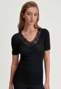 Zwarte T-shirt met een V-halsontwerp, voorzien van een bloemenkantafwerking rond de halslijn en korte mouwen. Gemaakt van zacht, geribbeld materiaal.