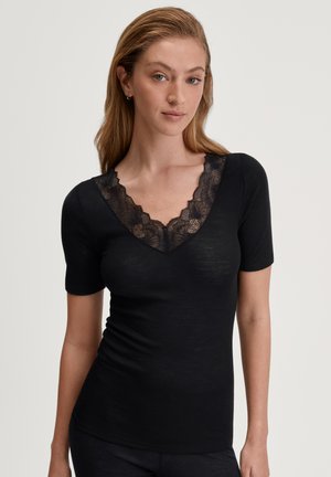 T-shirt nera con design a V, con bordino in pizzo floreale attorno al collo e maniche corte. Realizzata in morbido tessuto a coste.