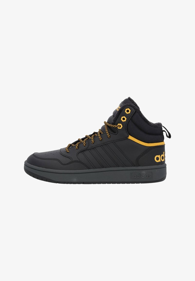 Zapatillas deportivas negras de corte alto hechas de cuero sintético con detalles en amarillo. Cuentan con cuello acolchado, detalles de cordones y suela de goma texturizada.