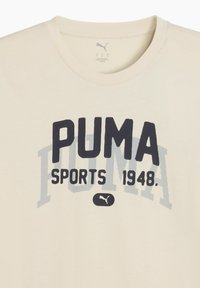 Kræmfarvet bomulds t-shirt med fed "PUMA" logo, "SPORTS 1948" tekst, og et lille logo ikon nær sømmen. Klassisk crew neck design.