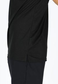 Mustapaitapaita lyhyillä hihoilla, valmistettu kevyestä kankaasta, jossa on kaareva helma ja sivuaukot, ja siinä on sileä, tekstuuri. 