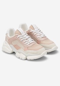 Chaussures de sport en mesh rose clair et suède avec lacets blancs, semelle blanche épaisse et marque discrète sur le talon. Design à bout arrondi.