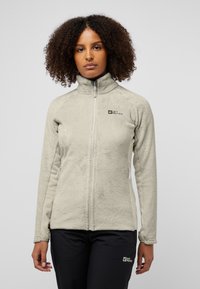 Fleecejack in lichtbeige met ritssluiting, hoge kraag en contrasterende zijpanelen; heeft het merkembleem op de borst.