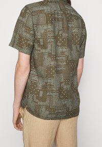 Korte mouw bruin gestreept shirt met verschillende motieven in lichtere tinten, gemaakt van een zachte stof met een ontspannen pasvorm.