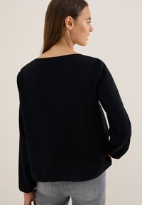 Zwarte blouse met lange mouwen, vierkante halslijn, soepele stof, relaxte pasvorm en subtiel gebogen zoom. Achteraanzicht toont een slank ontwerp en vloeiende silhouet.