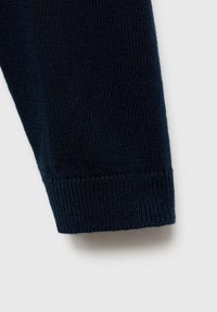 Mâneca unui pulover tricotat de culoare bleumarin închis, cu manșete cu dantelă; prezintă o textură netedă și un model uniform de cusături, fără hardware vizibil.