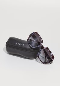 Ochelari de soare Vogue cu un cadru geometric, cu un model purpuriu închis și lentile întunecate, alături de un etui elegant, negru, cu fermoar.