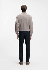 Ανοιχτό γκρι φούτερ με στενή εφαρμογή, στρογγυλή λαιμόκοψη και υφασμάτινη υφή. Συνδυασμένο με σκούρο μπλε παντελόνι, με εφαρμοστή σχεδίαση και πίσω τσέπη.