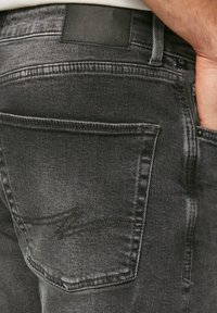 Czarne dżinsy z denimu mają teksturowane wykończenie oraz skórzaną metkę w pasie. Tylny kieszeń ozdobiona jest subtelnymi detalami w szwie.
