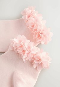Pink sokker med et struktureret strikket design, der har et dekorativt bånd af stofblomster ved kanten, som tilfører volumen og detalje.