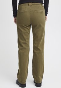 Pantalons cargo vert olive avec une coupe droite, comportant deux poches arrière et une texture de tissu lisse et durable. Chaussures noires visibles.