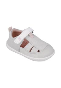 Zapato de tela gris claro con lados abiertos, correa de Velcro, suela blanca y sutiles acentos en rosa. Presenta material texturizado y un diseño recortado.