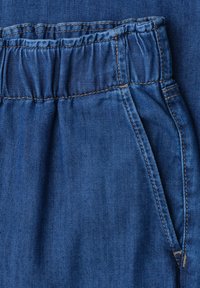 Denimstof med elastisk talje og sidelomme med synlige syninger.