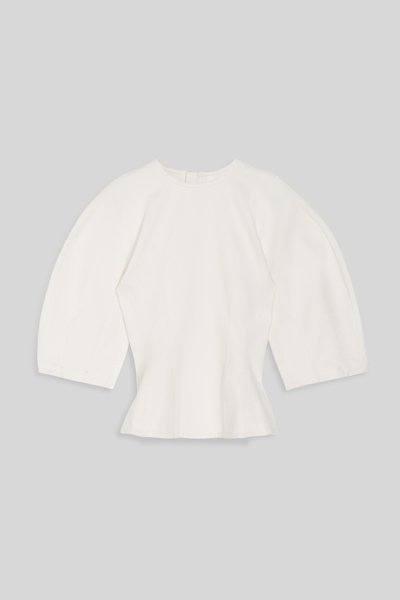 Witte aangesloten blouse met brede driekwartsmouwen en ronde halslijn op grijze achtergrond.