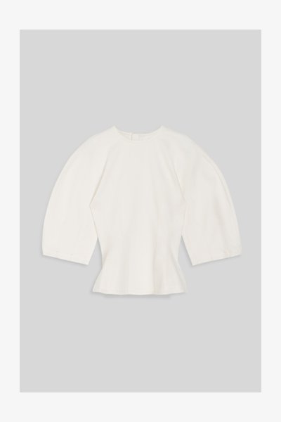 Witte aangesloten blouse met brede driekwartsmouwen en ronde halslijn op grijze achtergrond.