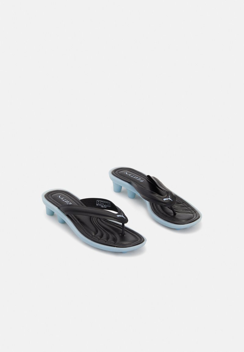 Black and blue Puma slide sandals with low block heels and thong straps on a white background.