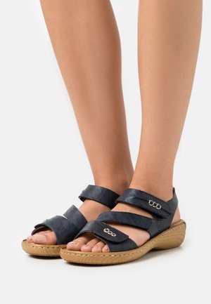 Dark blue leather sandals with three wide straps, open toe design, and a textured, light brown rubber sole. Silver hardware accents.