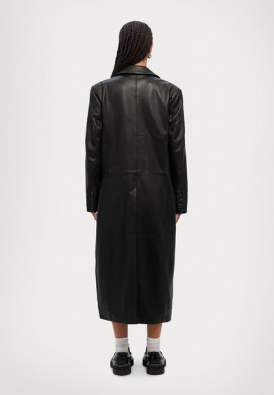 Long black leather coat with a smooth texture, featuring a classic collar and buttoned cuffs, extending to mid-calf length.