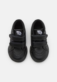 Svarte lærersko til småbarn med borrelås, rund tå, teksturert overflate og Vans-logo på tungen. Glatt finish og broderte detaljer.