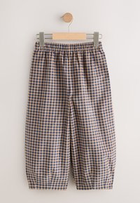 Pantalon ample avec taille élastique et motif à carreaux bleu et beige suspendu sur un cintre en bois sur fond blanc.