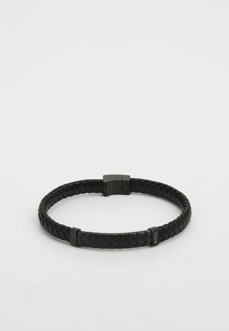 Pulsera de cuero trenzado negro con un acabado suave, con un cierre metálico. Los acentos muestran la marca "BOSS" en uno de los segmentos.