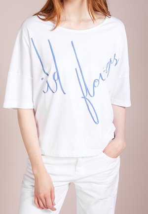 Wit katoenen T-shirt met een losse pasvorm en korte mouwen, met blauwe cursieve tekst waarop "wild flowers" staat. Gladde textuur, casual ontwerp.