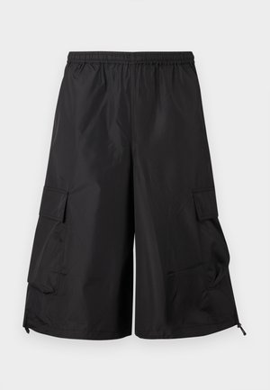 Μαύροι cargo σορτς με φαρδιά γραμμή, ελαστική μέση και τσέπες με καπάκι σε κάθε πλευρά, παρουσιάζονται σε απλό φωτεινό φόντο.