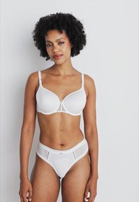 White seamless bra with adjustable straps and lace accents paired with matching white high-waisted briefs featuring a patterned design.