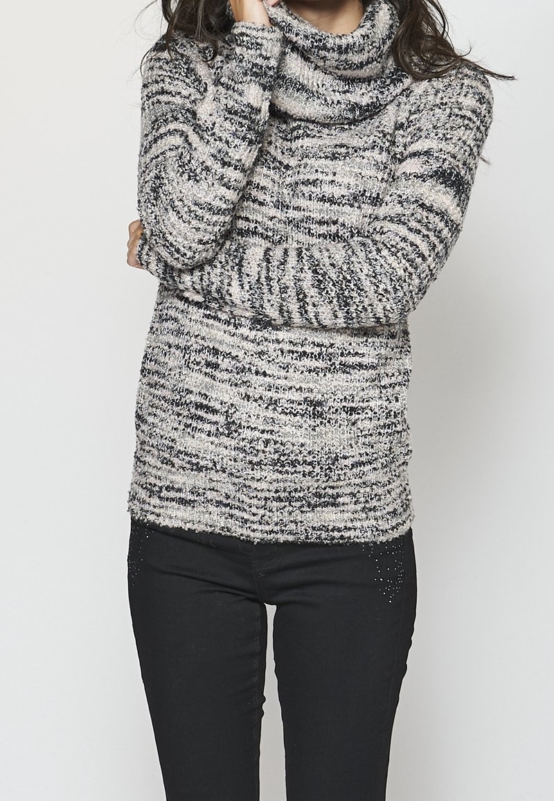 Pull à col bénitier en tissu doux et texturé avec un motif rayé noir et blanc. Assorti à un pantalon en denim noir, avec de légères ornements discrètes.