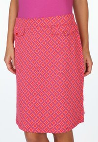 Pink patterned skirt featuring a diamond design, two front pockets with buttons, and a smooth fabric texture.