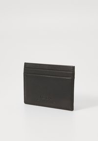 Black leather cardholder featuring four card slots, embossed logo detail, smooth texture, and minimalistic design.