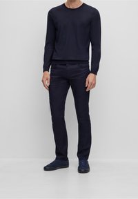 Mörkblå långärmad skjorta, figurnära passform, ribbade muddar. Kombinerad med mörkblå smala byxor och matchande mockasiner, alla i enfärgat utförande.