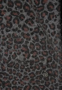 Graues Strickmaterial mit einem Leopardenmuster in Schwarz und Braun. Besitzt ein kleines metallisches Akzentdetail. Weiche Textur.