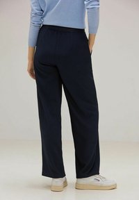 Marina ribbade byxor med elastisk midja, som har en avslappnad passform och ett mjukt, strukturerat tyg. Bärs med vita sneakers.