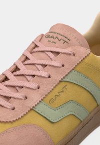 Semskede sneakers med rosa, gule og grønne paneler, teksturerte overflater, flate lisser og en tan gummi såle med merkevaredetalj.