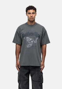 Losse grijze katoenen t-shirt met korte mouwen, voorzien van vlinderafdrukken en gestileerde tekst. Crew neck ontwerp met een licht verweerd uiterlijk.