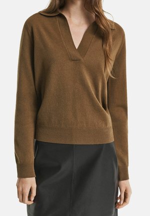 Brązowy sweter z długim rękawem i dekoltem w serek w zestawieniu z czarną spódnicą, noszony przez kobietę z luźno rozpuszczonymi włosami, pokazany od szyi do bioder.