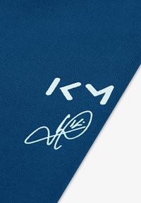 Tkanina v mornarsko modri barvi z gladko teksturo, ki prikazuje belo grafično besedilo in podpisno zasnovo v spodnjem desnem kotu.