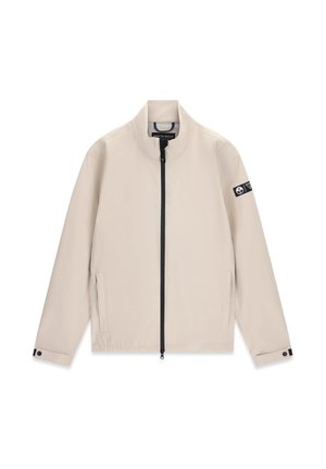 Veste légère beige avec fermeture éclair avant noire, deux poches latérales, col montant, poignets réglables et écusson logo sur la manche gauche.