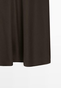 Tissu brun fluide qui tombe en douceur, avec un bord droit et un léger éclat. La texture semble douce et légère, idéale pour être superposée.